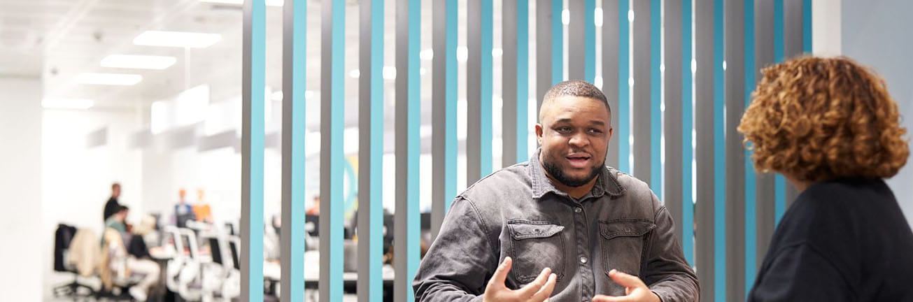 A man and a woman discuss cybersecurity in a modern office, highlighting digital safety, risk management, and secure business operations.