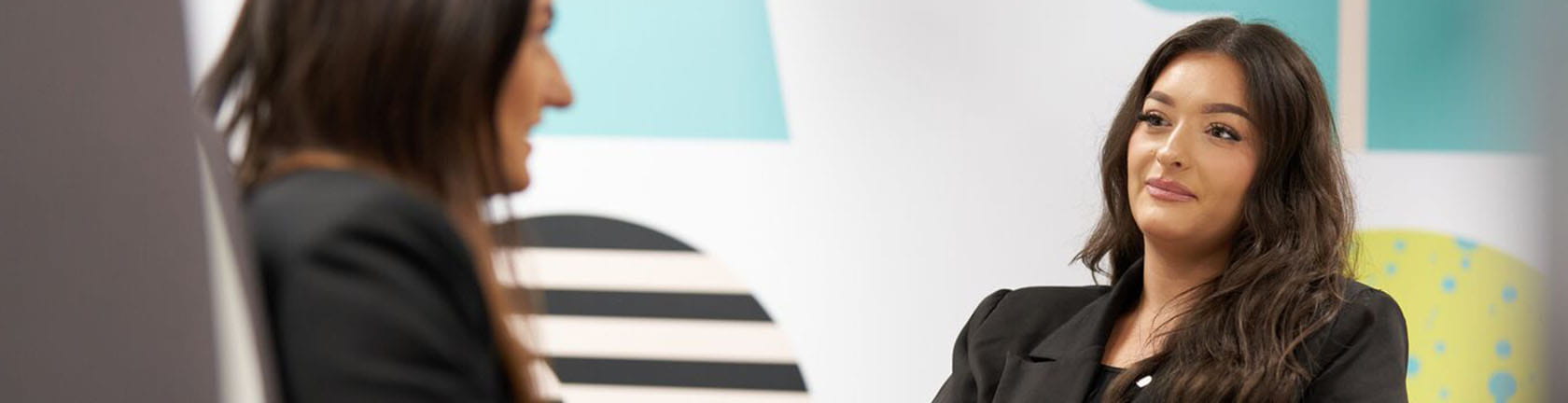 A woman engages in a conversation, representing a welcoming contact point for candidates and associates.