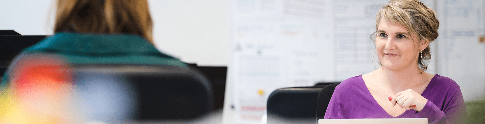 A professional recruiter engaging with a candidate in a modern office setting, discussing hiring and talent deployment strategies.