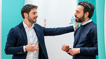 Two men in discussion in a hallway, symbolizing open dialogue in public affairs. Two men in discussion in a hallway, symbolizing open dialogue in public affairs.