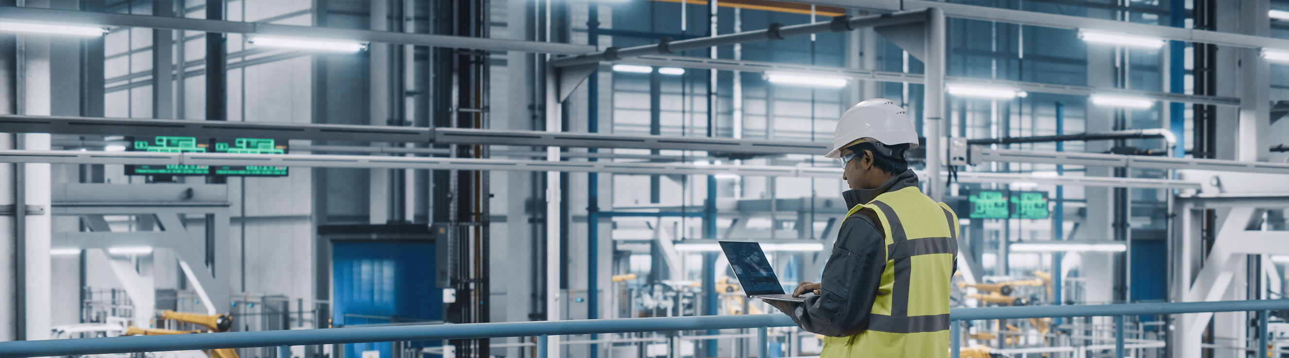 Car Factory Engineer in High Visibility Vest Using Laptop Computer Car Factory Engineer in High Visibility Vest Using Laptop Computer