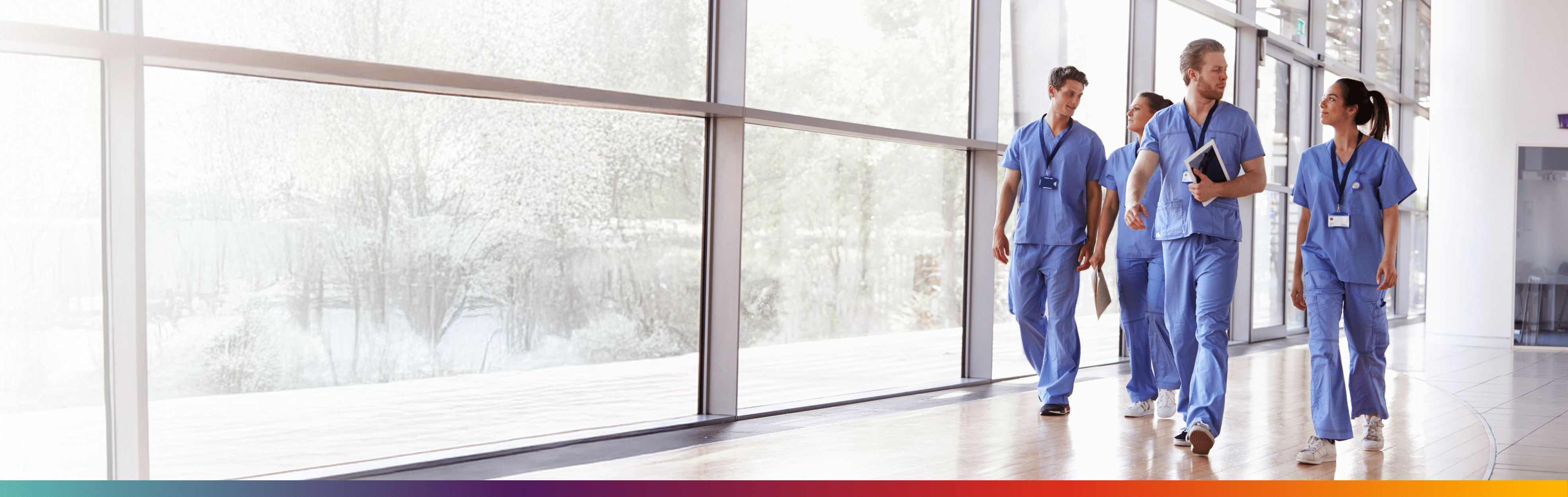 Quattro professionisti sanitari laureati che camminano lungo un corridoio