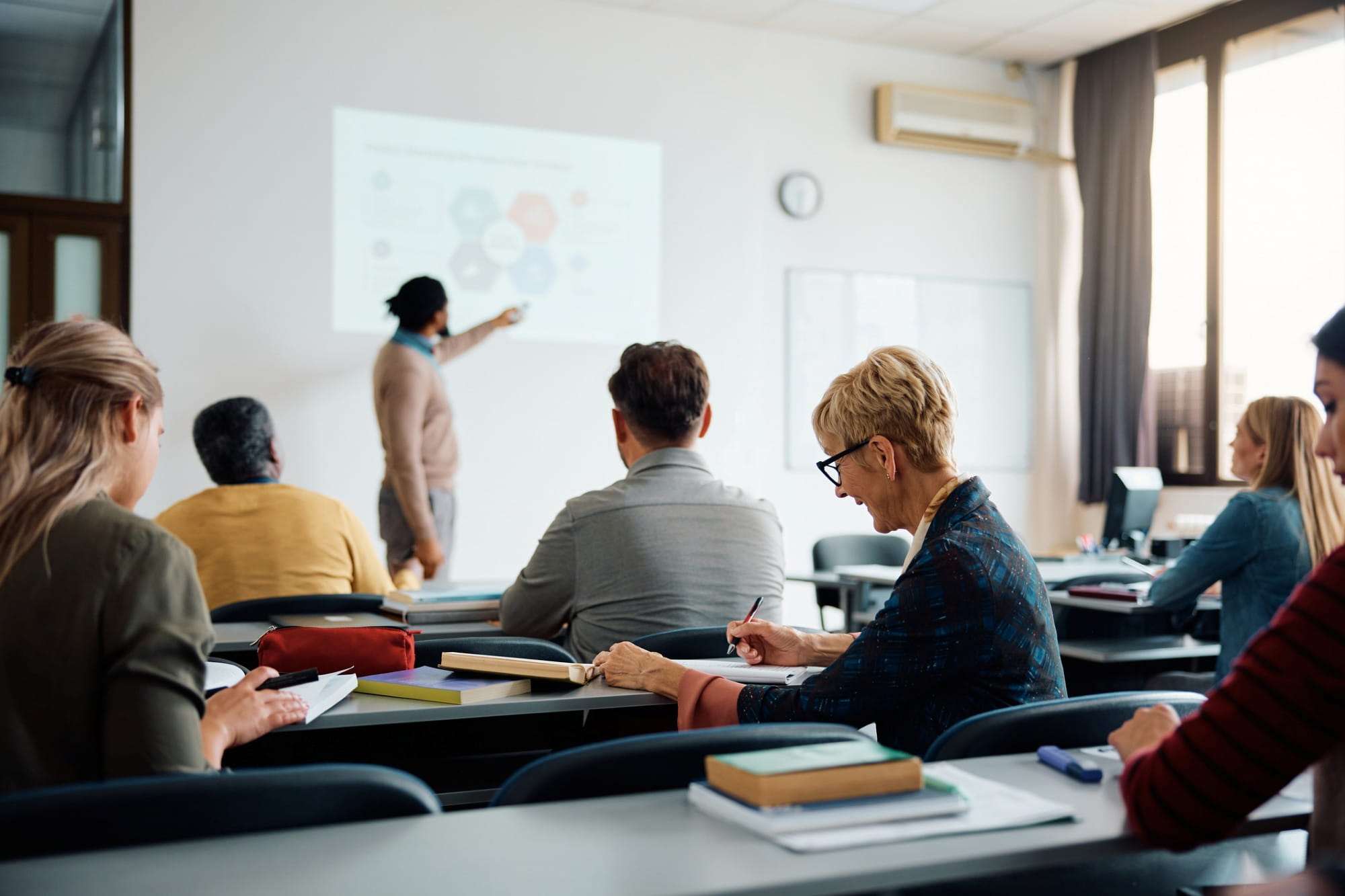 Smiling adult woman taking notes during a training or education class. Smiling adult woman taking notes during a training or education class.