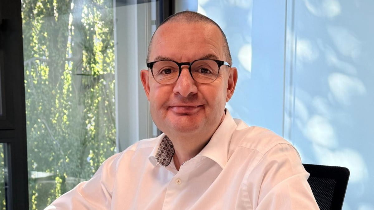 Portrait photograph of Raphael Naoux seated in an office in front of a window wall.