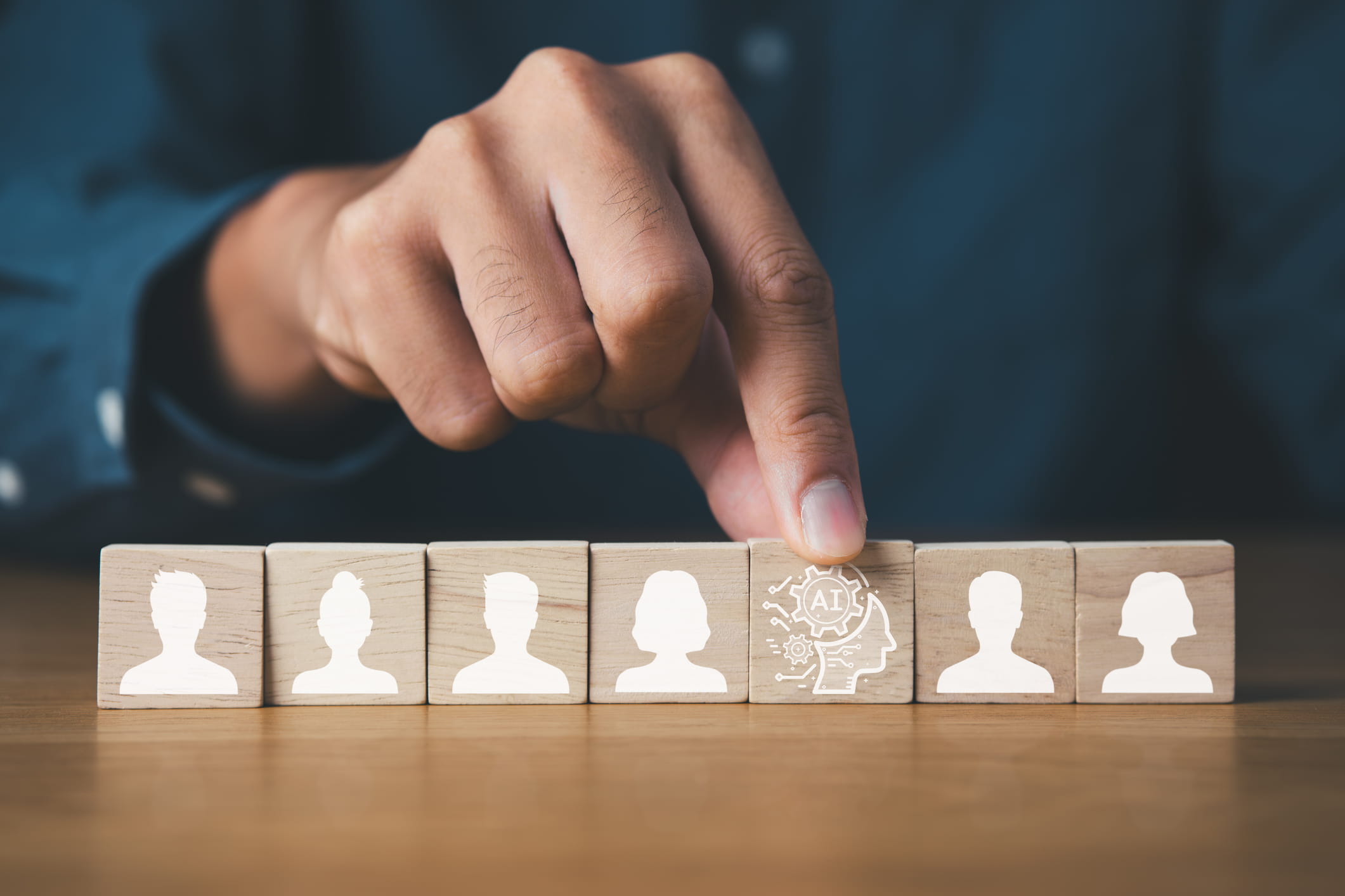 Mano che sposta un cubo con un’icona di IA tra vari cubi con icone di persone. Mano che sposta un cubo con un’icona di IA tra vari cubi con icone di persone.