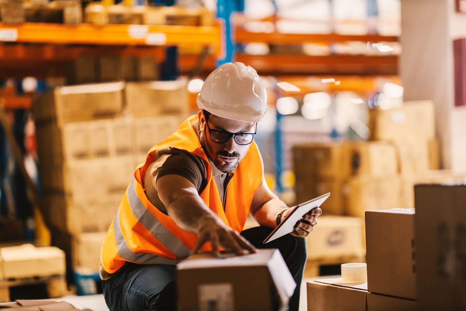 Un addetto temporaneo alla logistica in un magazzino mentre controlla un pacco Un addetto temporaneo alla logistica in un magazzino mentre controlla un pacco